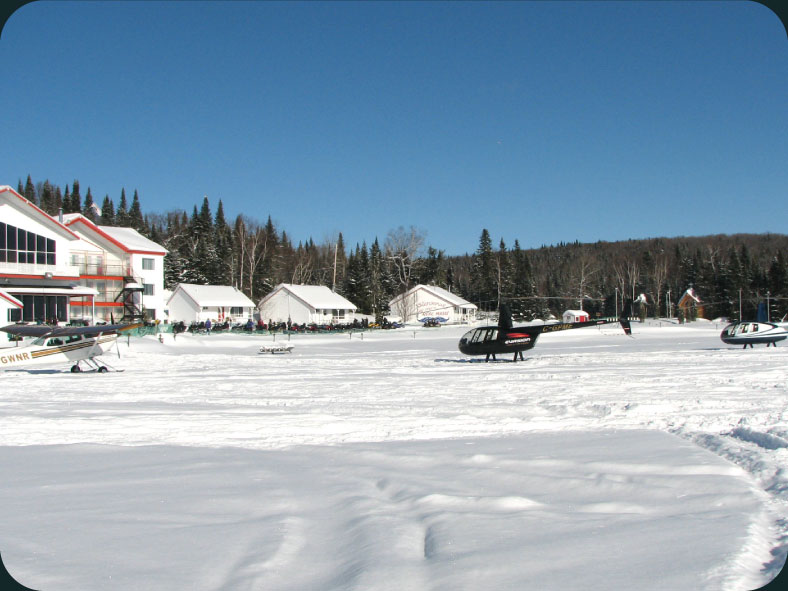 Snow-covered buildings and a helicopter beside the outfitter