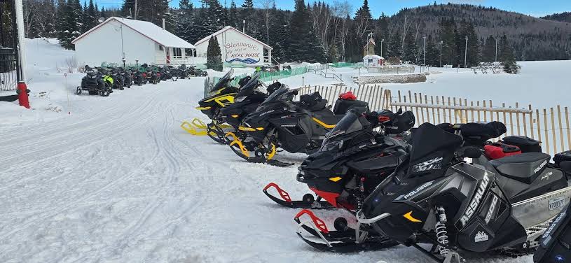 Snowmobiles parked in front of the lodge and fenced enclosure